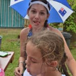 Woman with Australia umbrella hat sitting next to girl — Caravan Park in Kinka Beach, QLD