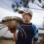 Boy Holding Large Mud Crab — Caravan Park in Kinka Beach, QLD